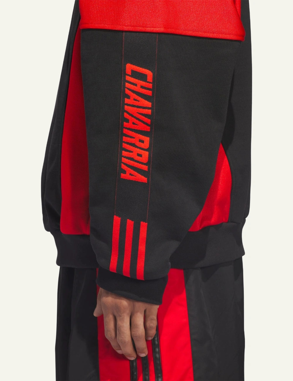 CHAVARRIA graphic sleeve detail with red triple stripes on black mockneck jumper.