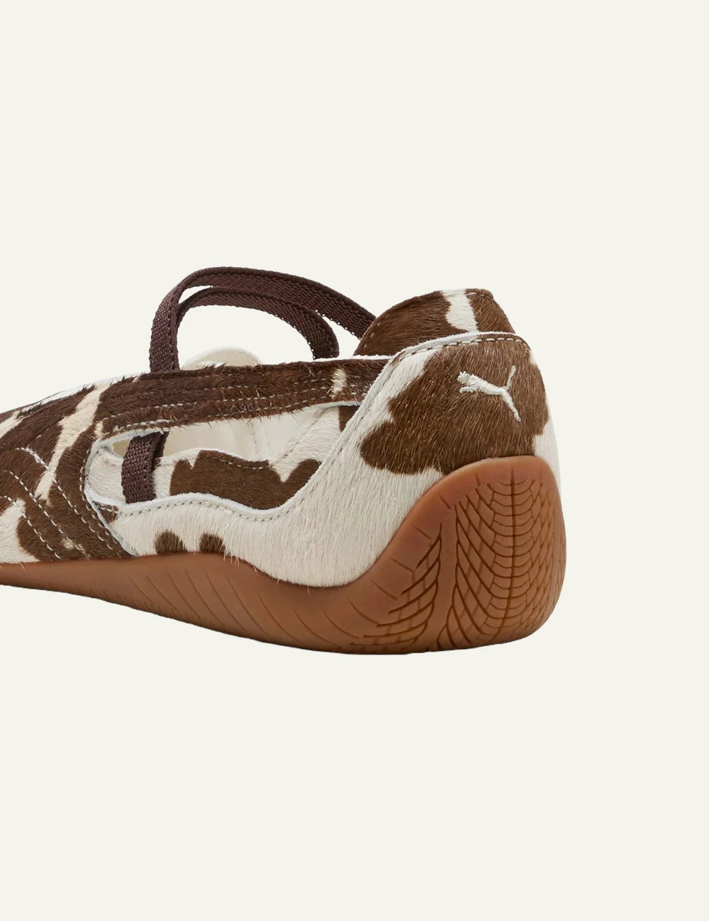 Brown and white cow print ballet flats with elastic straps back view