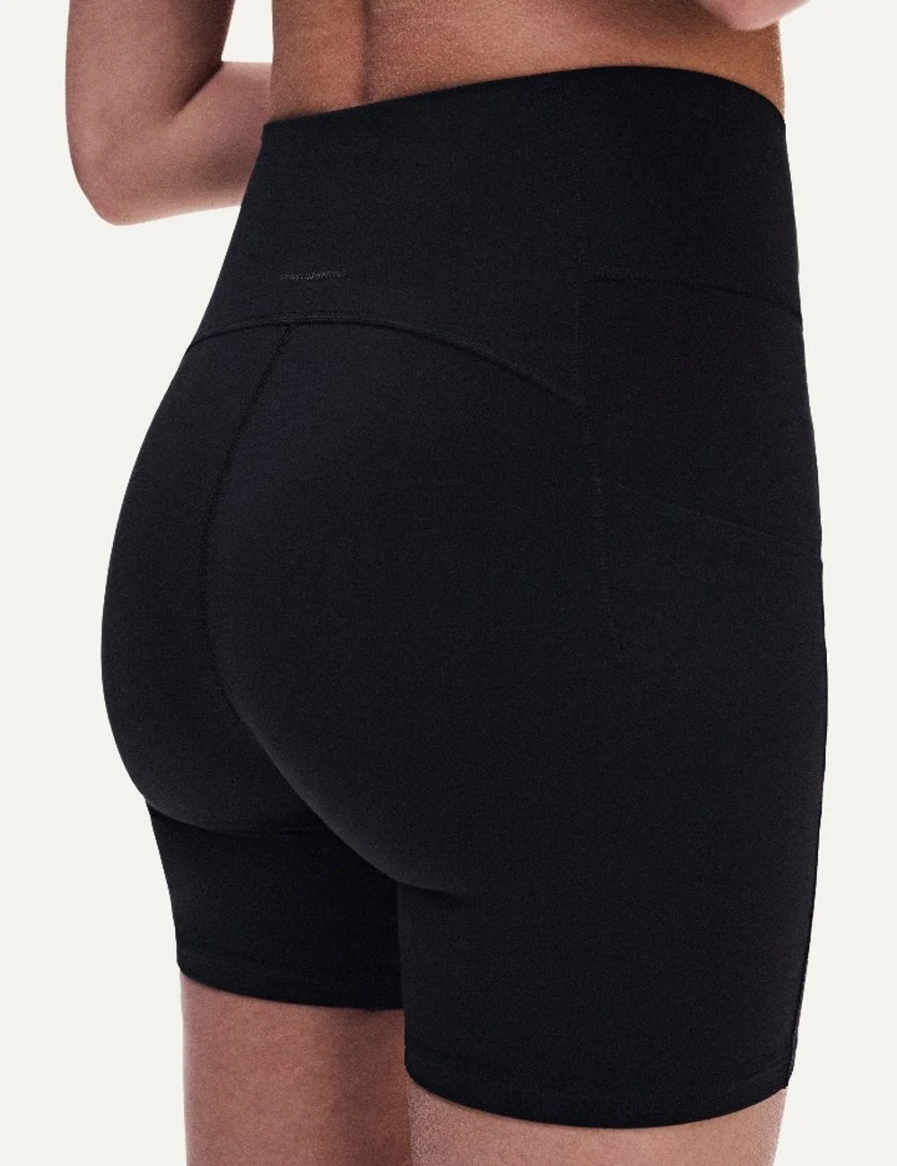 On women's black high-waisted biker shorts with close fit, soft SenseTec fabric, four-way stretch, seamless front, wide supportive waistband and side phone pocket back