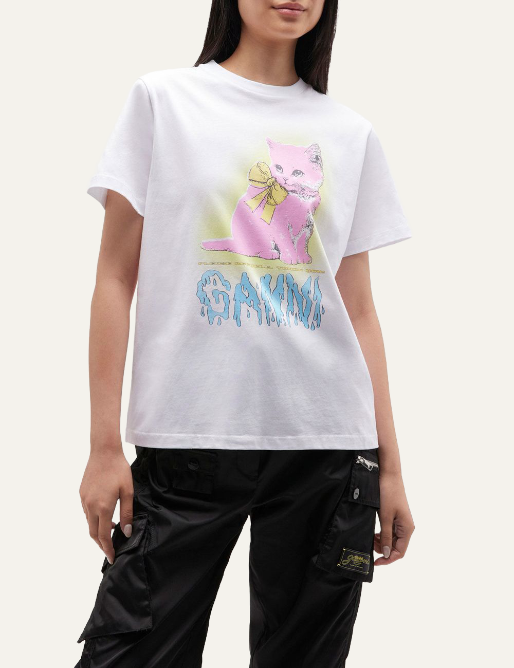 Model wearing white Ganni T-shirt with pink kitten graphic and yellow bow, styled with black cargo pants.
