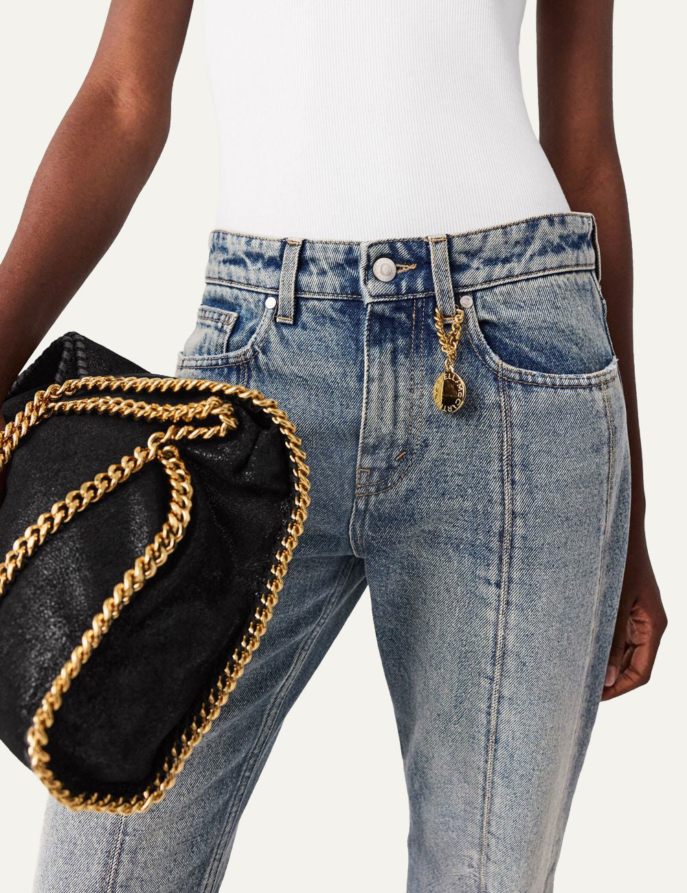 Stella McCartney wide leg jeans waist detail, gold logo charm, denim close-up
