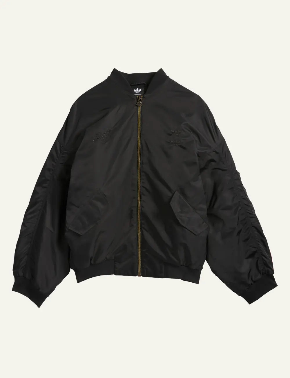 Black satin bomber jacket Adidas x Willy Chavarria σε flat lay με minimal detailing.