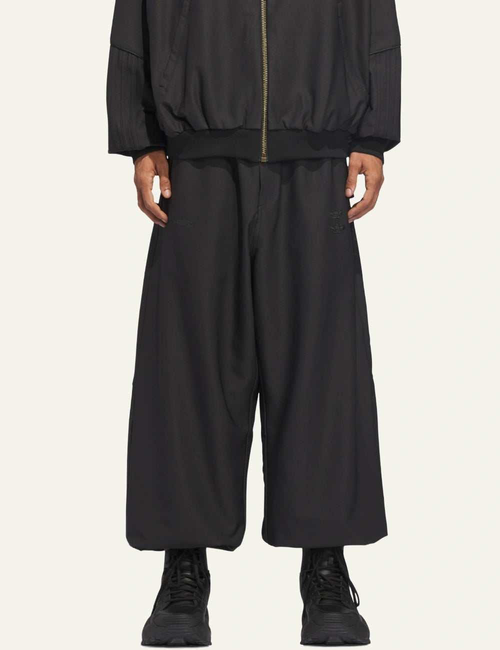 Model wearing Adidas x Willy Chavarria twill track trousers σε wide, relaxed silhouette.