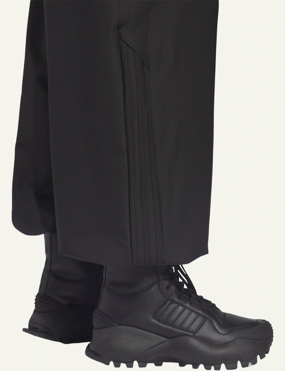 Lower hem detail showing tonal triple stripes on Adidas x Willy Chavarria twill trousers.