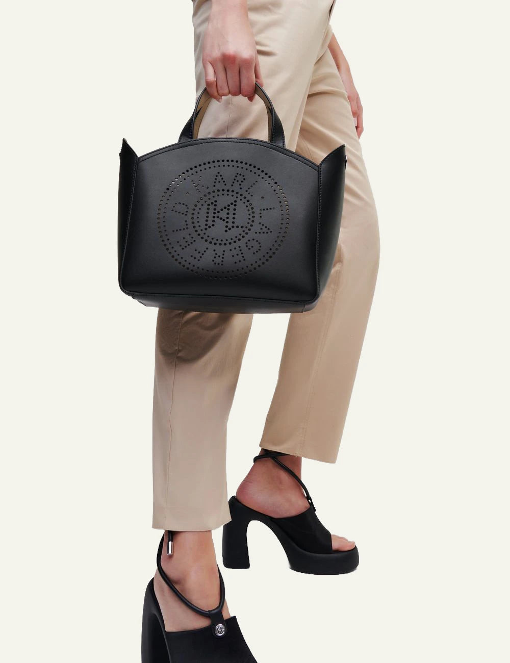 Model holding Karl Lagerfeld black perforated tote bag worn crossbody
