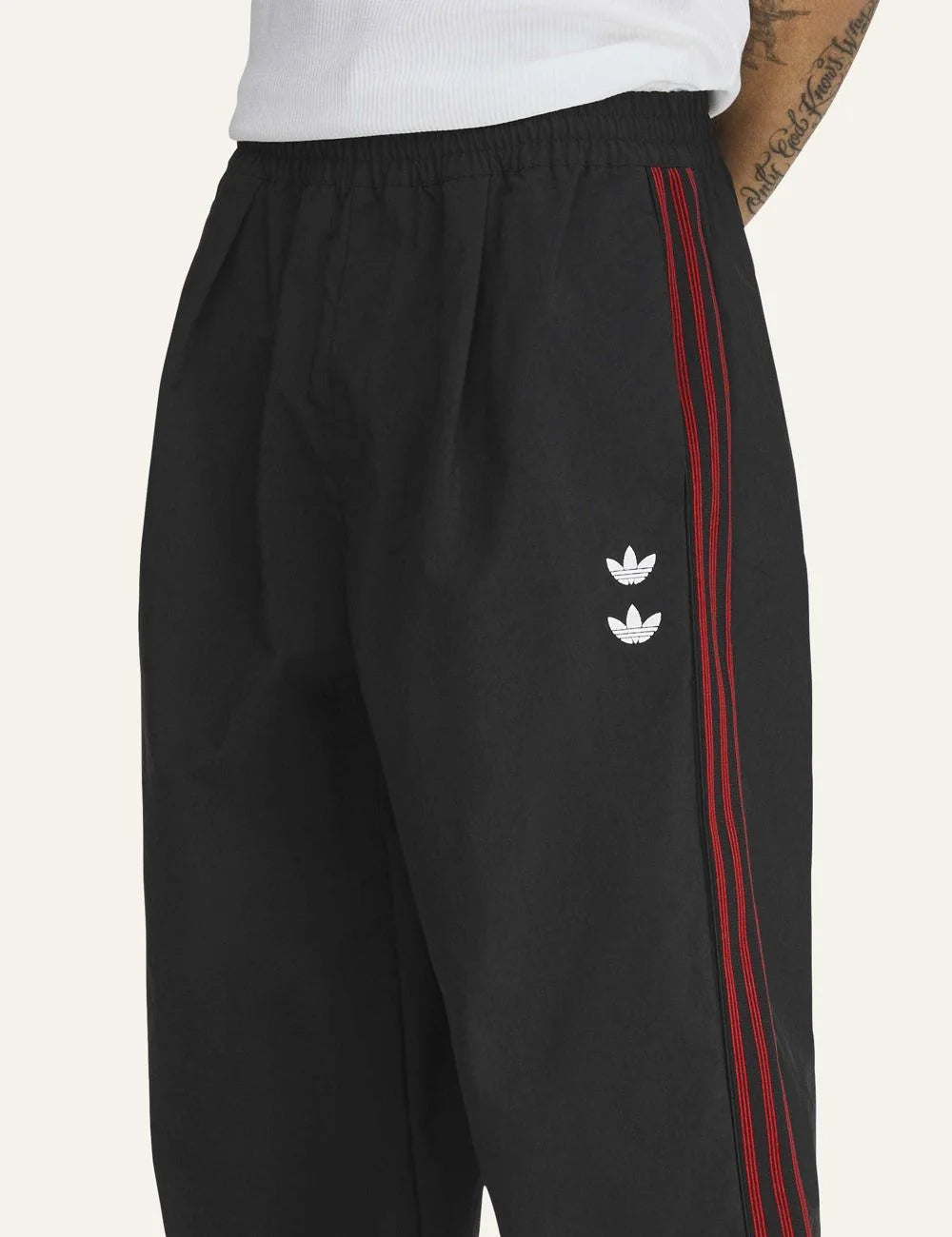 Men's adidas black woven track pants with burgundy side stripes, embroidered logos and rose artwork detail