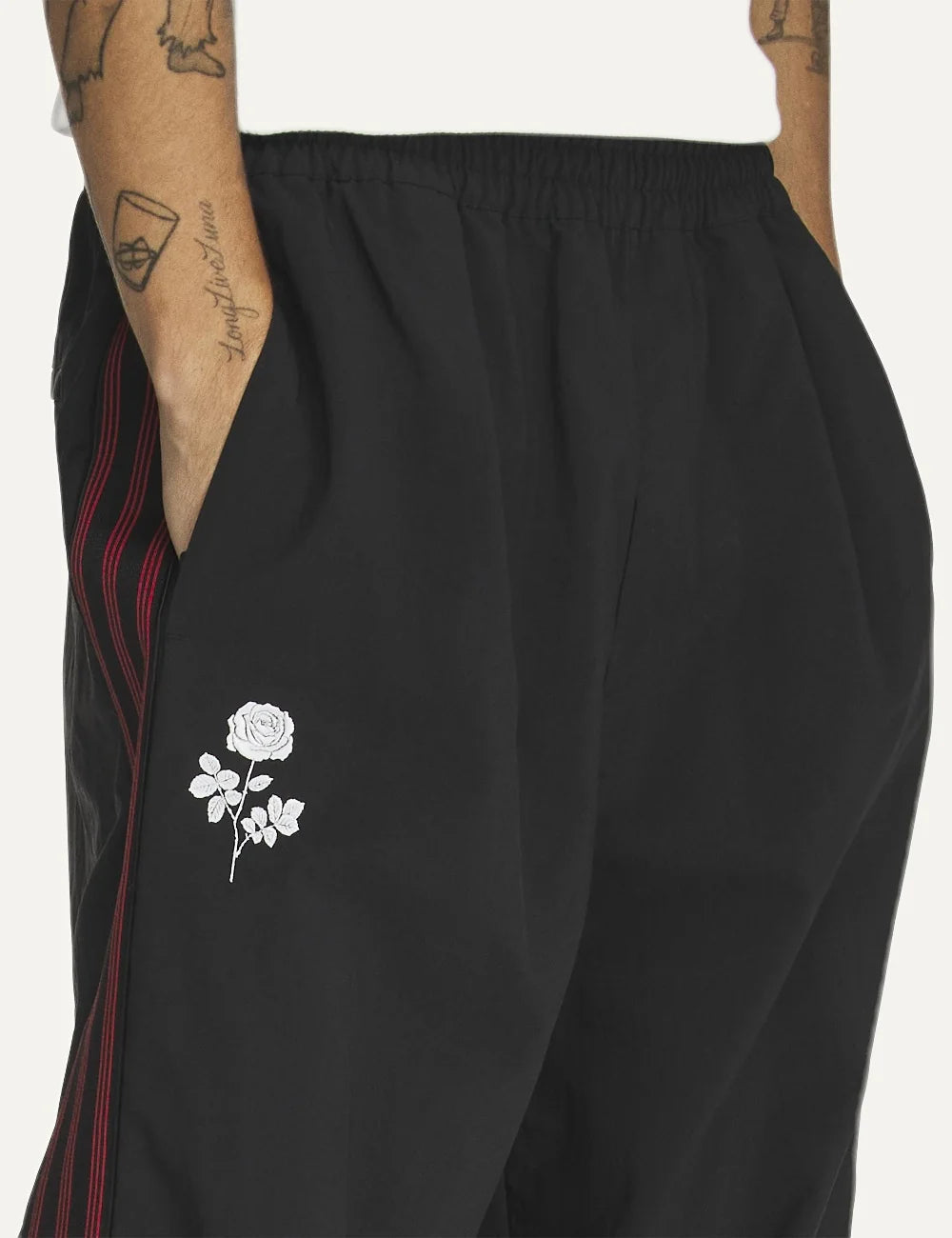 Men's adidas black woven track pants with burgundy side stripes, embroidered logos and rose artwork detail