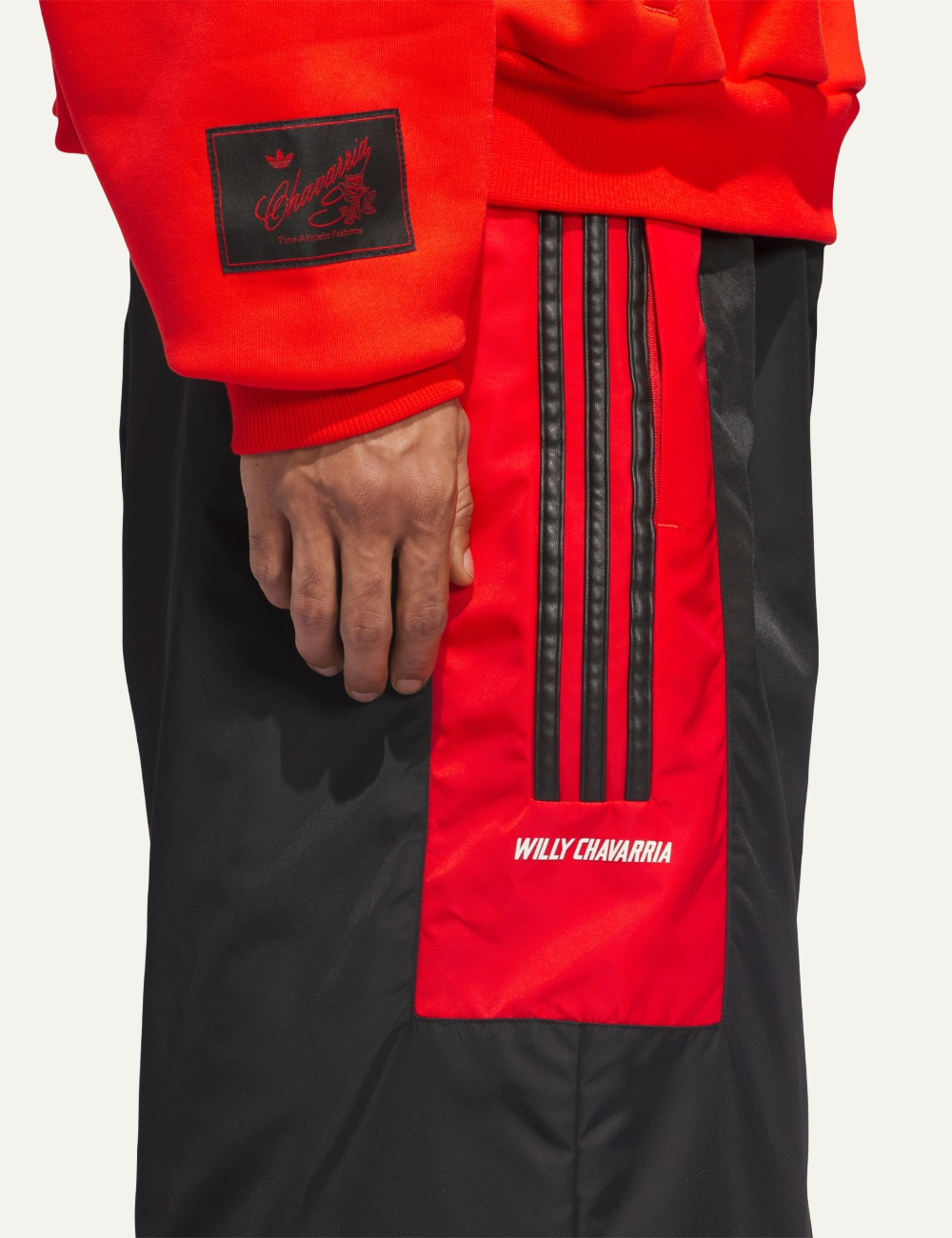 Side detail with triple black stripes and WILLY CHAVARRIA branding on Adidas fleece track pants.