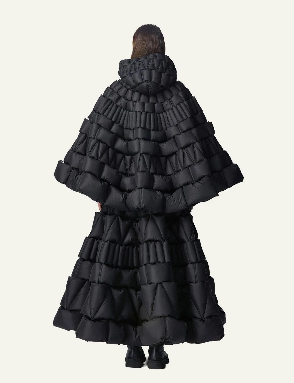 Back view of Raxxy black 3D quilted cape puffer, με tiered 3D padding και voluminous architectural design.