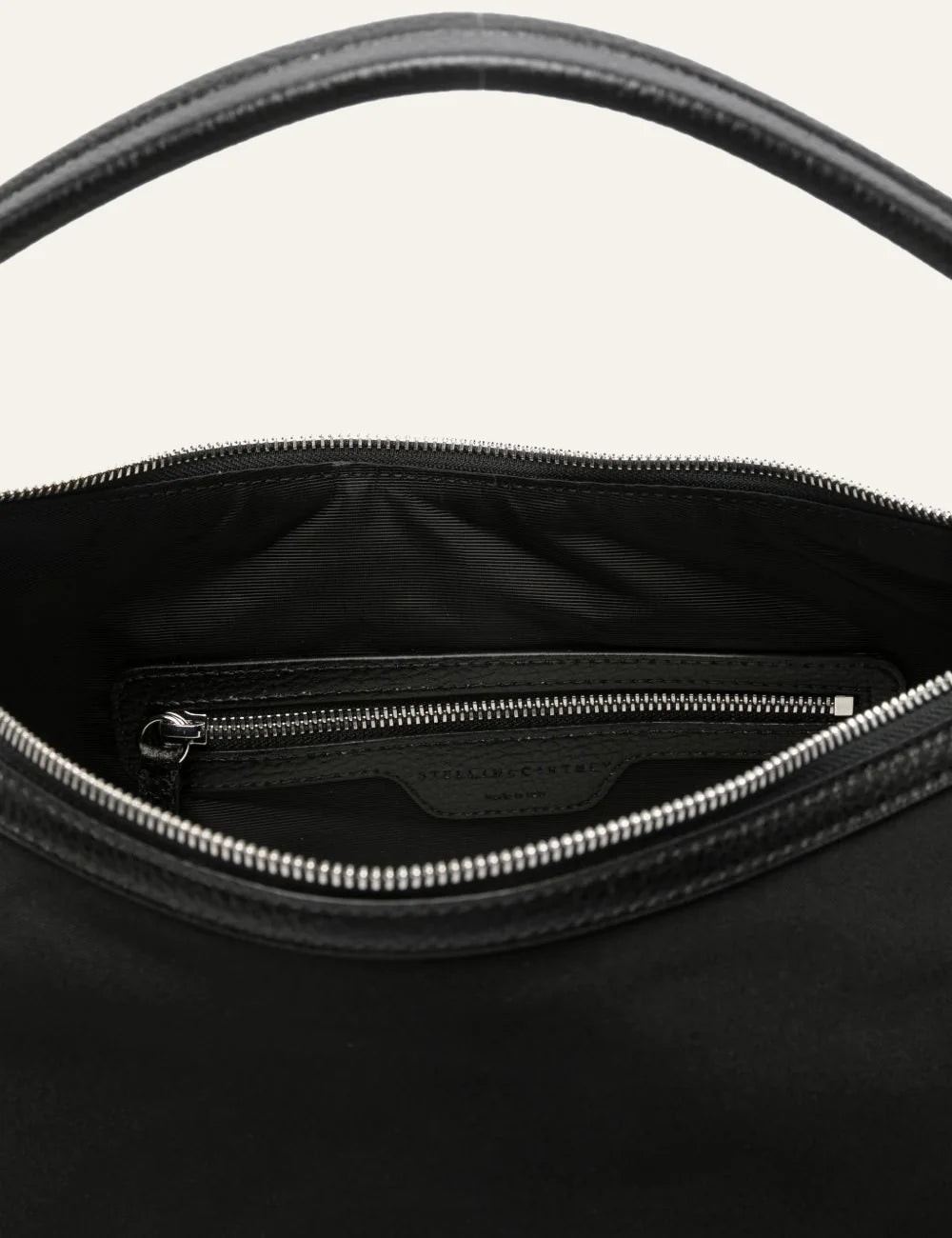 “Interior view of Stella McCartney Dartmoor bag with zip pocket and branded lining in black.”