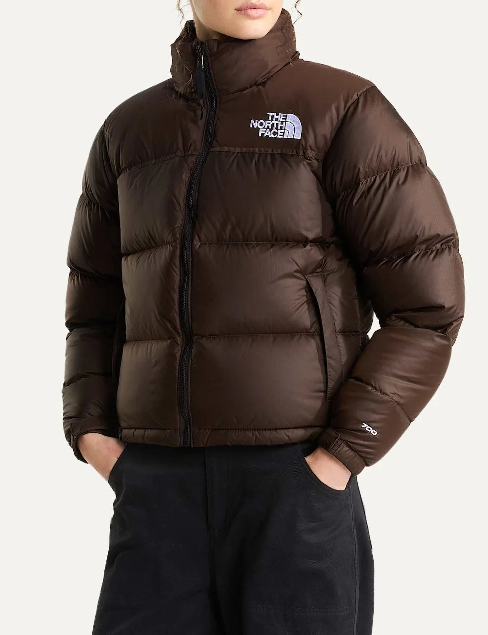 The North Face women's 1996 Retro Nuptse puffer jacket in dark chestnut brown with quilted down panels, high collar, front zip and white chest logo model