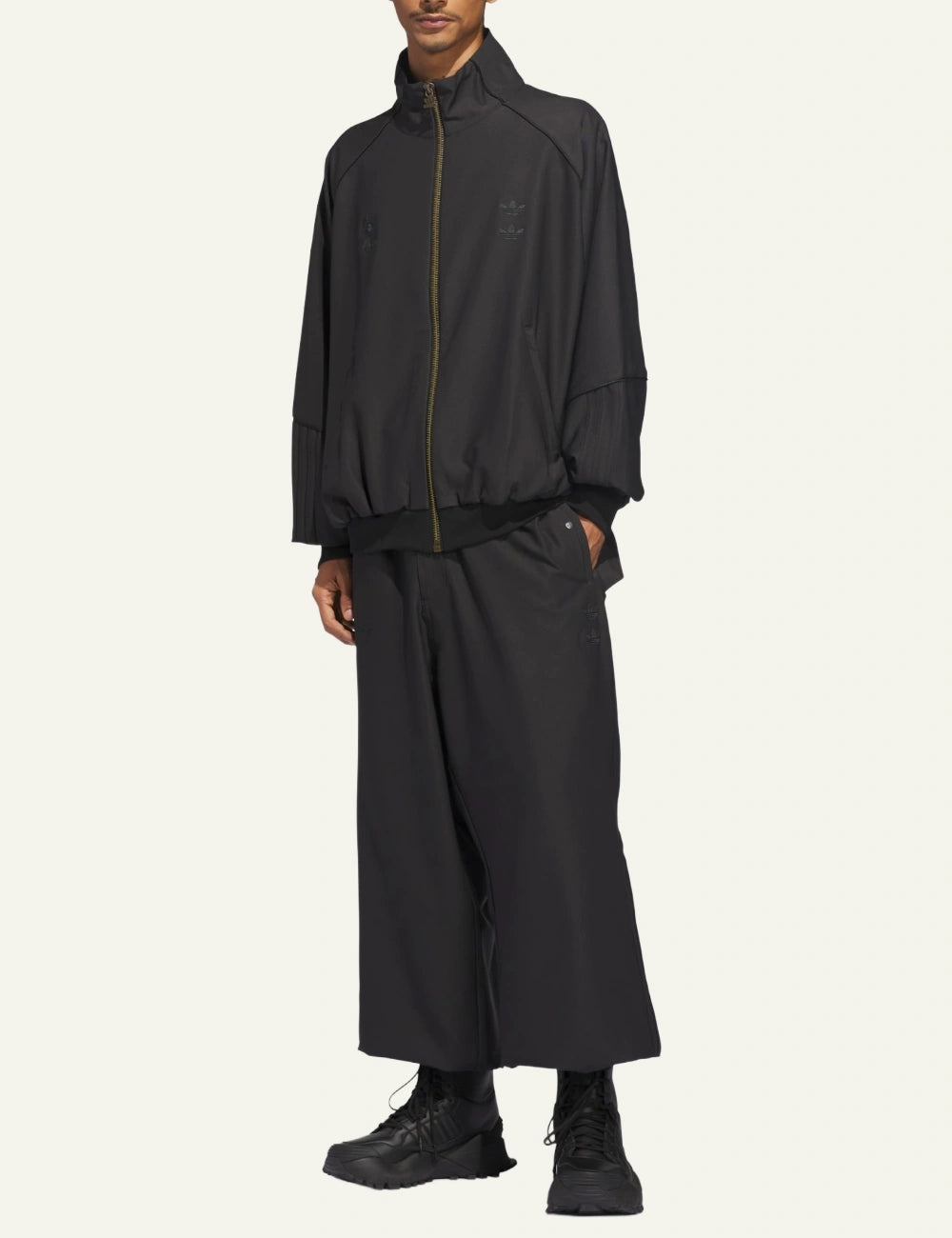 Side full-body view of Adidas x Willy Chavarria twill jacket paired with wide-leg pants.