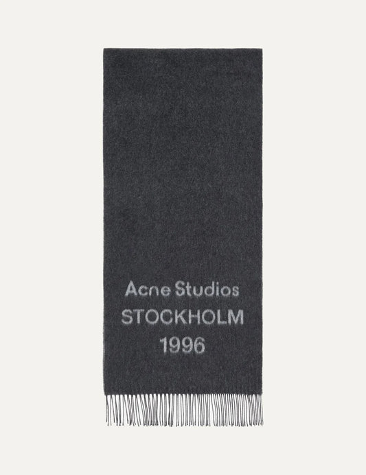 Acne Studios men's dark charcoal grey wool jacquard scarf featuring contrasting Acne Studios Stockholm 1996 logo lettering and fringed ends.