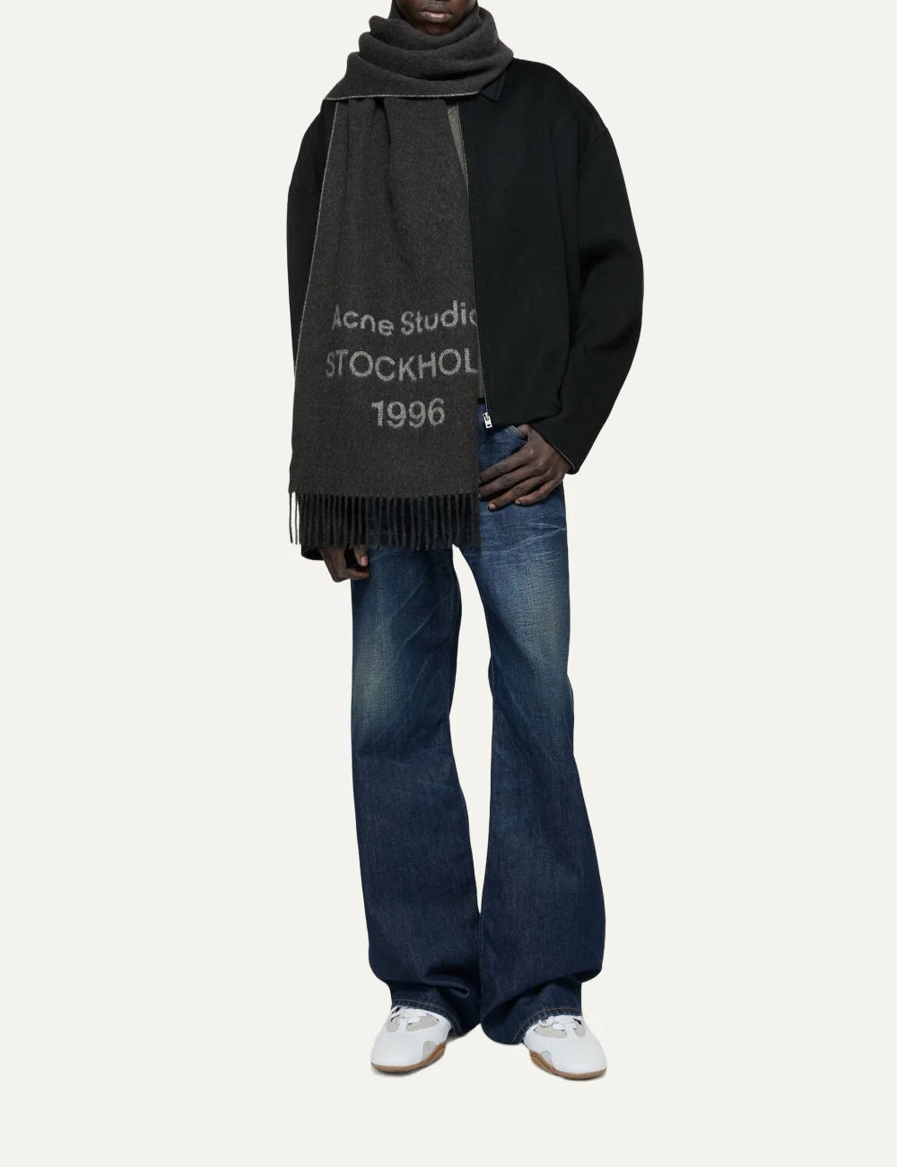 Acne Studios men's dark charcoal grey wool jacquard scarf featuring contrasting Acne Studios Stockholm 1996 logo lettering and fringed ends model