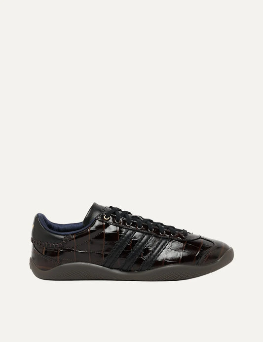 Adidas x Wales Bonner Karintha Crocodile low-top sneakers in glossy dark brown croc-embossed finish with black three stripes, lace-up fastening and dark rubber sole.