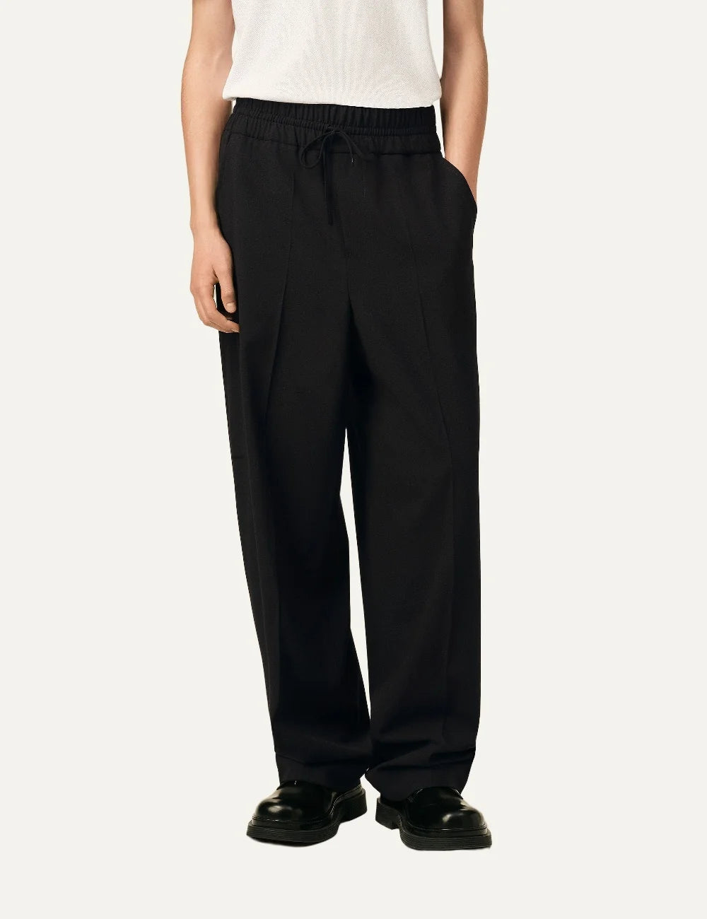 Ami Paris unisex black relaxed-fit trousers with an elasticated drawstring waist, side pockets and straight legs model