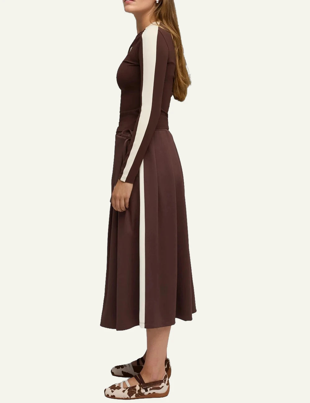 Brown and white cow print ballet flats with elastic straps model view