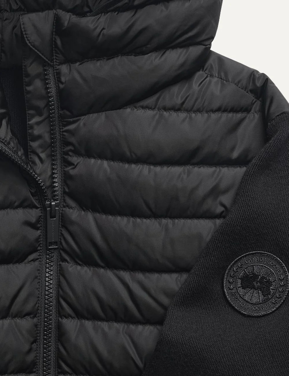 Women's Canada Goose HyBridge Hayes black hybrid down jacket with quilted front, down-filled hood, merino wool sleeves, full zip closure and logo patch. detail