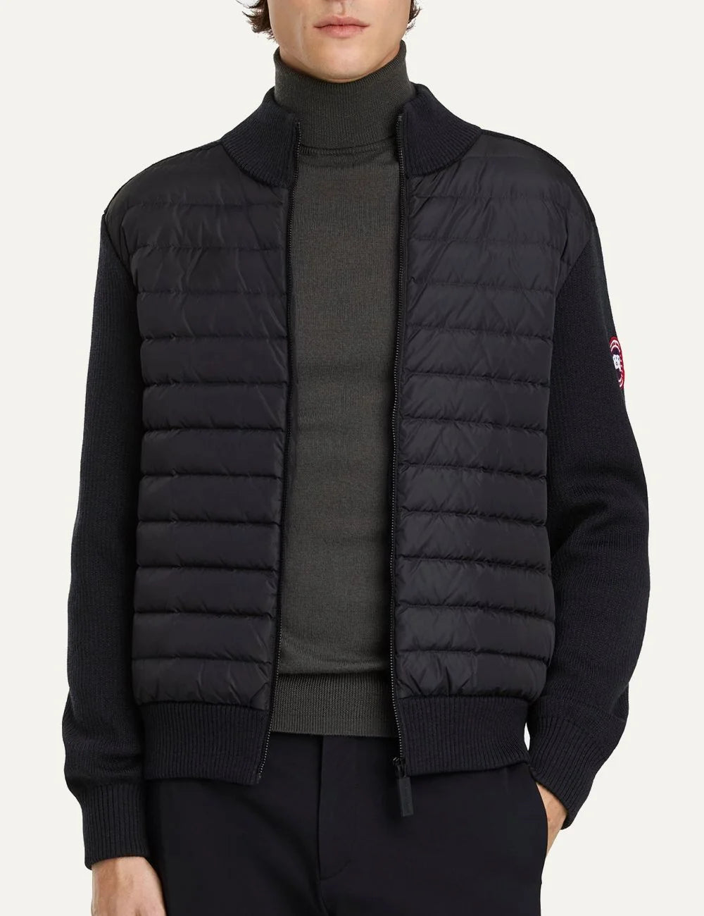 Canada Goose men's HyBridge Knit Jacket in black merino wool with down-filled quilted front, ribbed collar and cuffs, zip closure and logo patch model