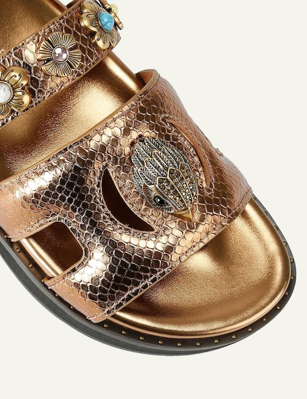 Kurt Geiger gold leather sandal snake texture floral studs eagle logo angled view.