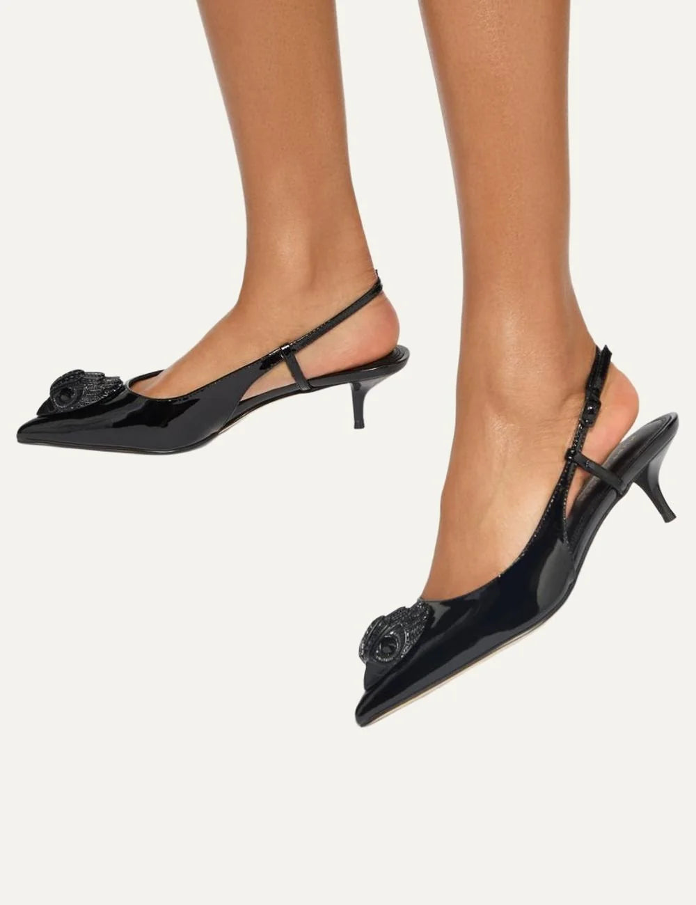 Kurt Geiger London black patent leather slingback pumps with pointed toe, crystal-embellished eagle head, adjustable strap and kitten heel model
