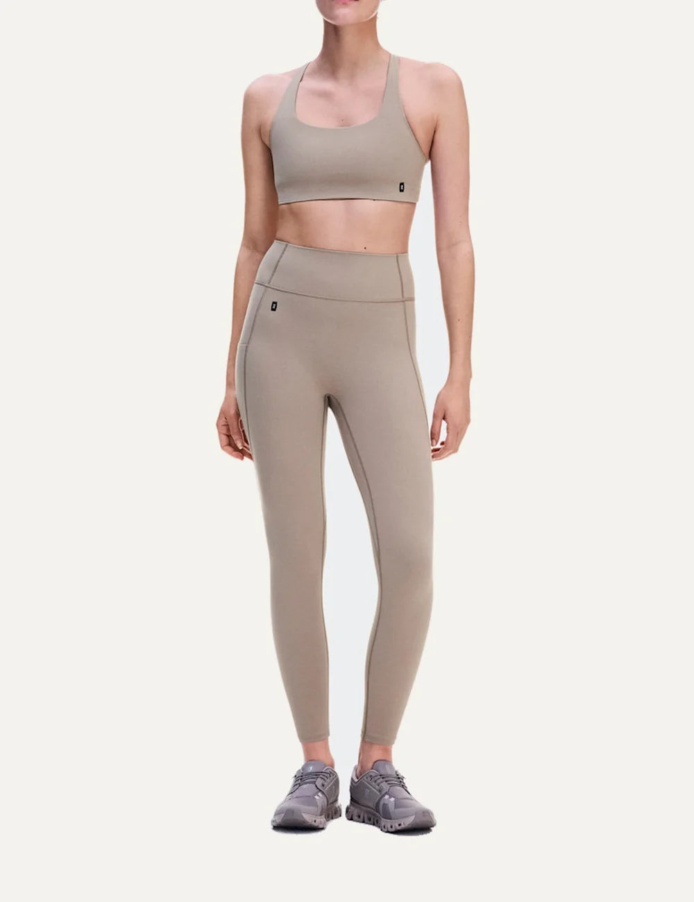 On women's beige sports bra with low support, scoop neckline, strappy open back, soft SenseTec stretch fabric, gentle elastic underband and moisture-wicking mesh lining model