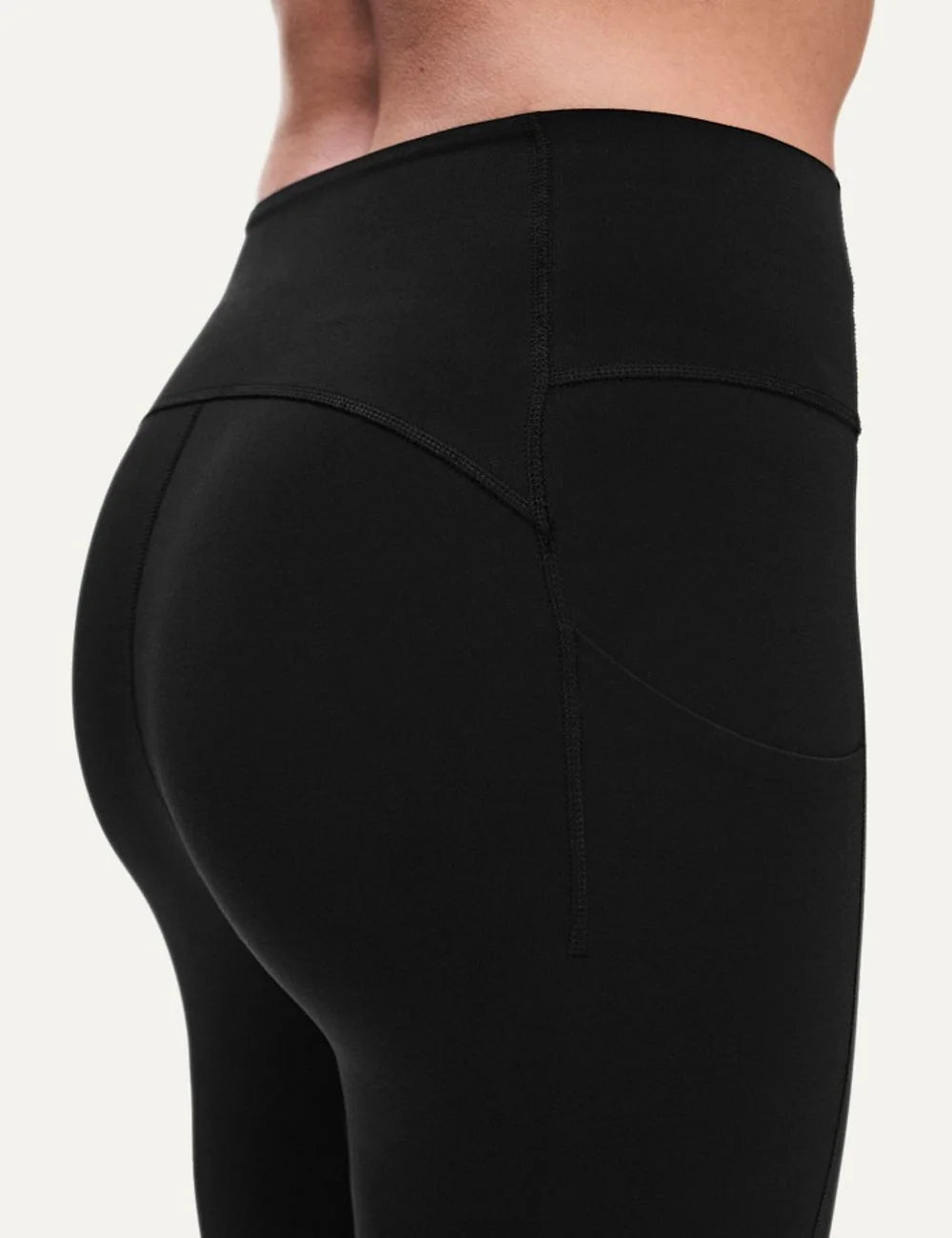 On women's black high-waisted athletic leggings with close fit, ankle length, soft SenseTec fabric, four-way stretch, seamless front and side phone pocket detail