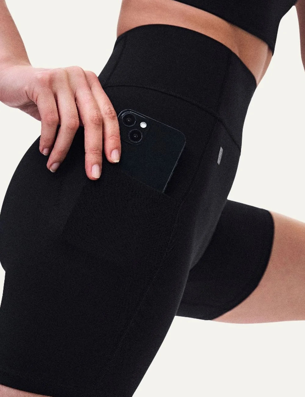 On women's black high-waisted biker shorts with close fit, soft SenseTec fabric, four-way stretch, seamless front, wide supportive waistband and side phone pocket detail