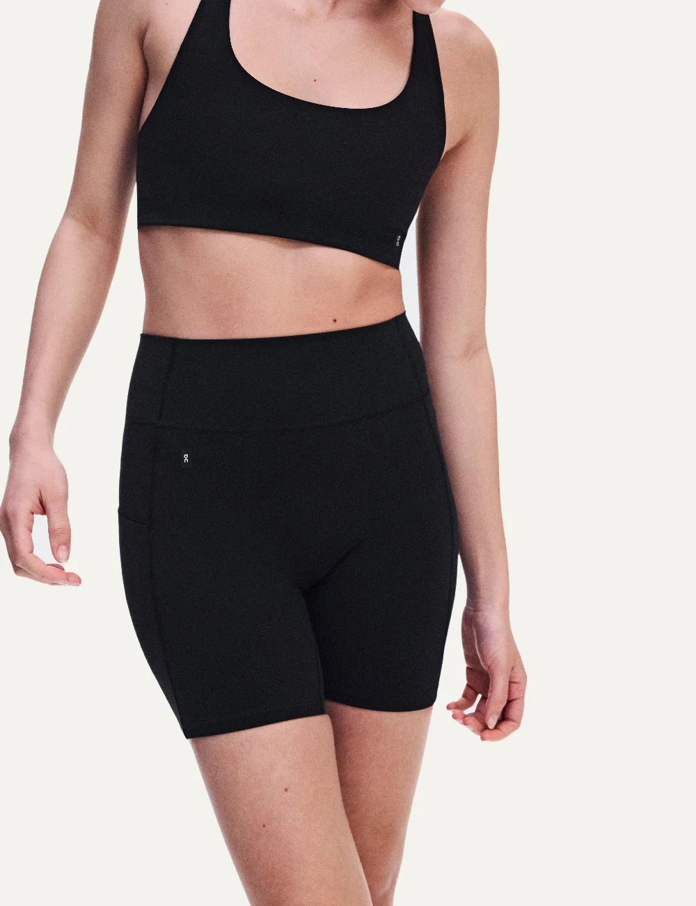 On women's black high-waisted biker shorts with close fit, soft SenseTec fabric, four-way stretch, seamless front, wide supportive waistband and side phone pocket model