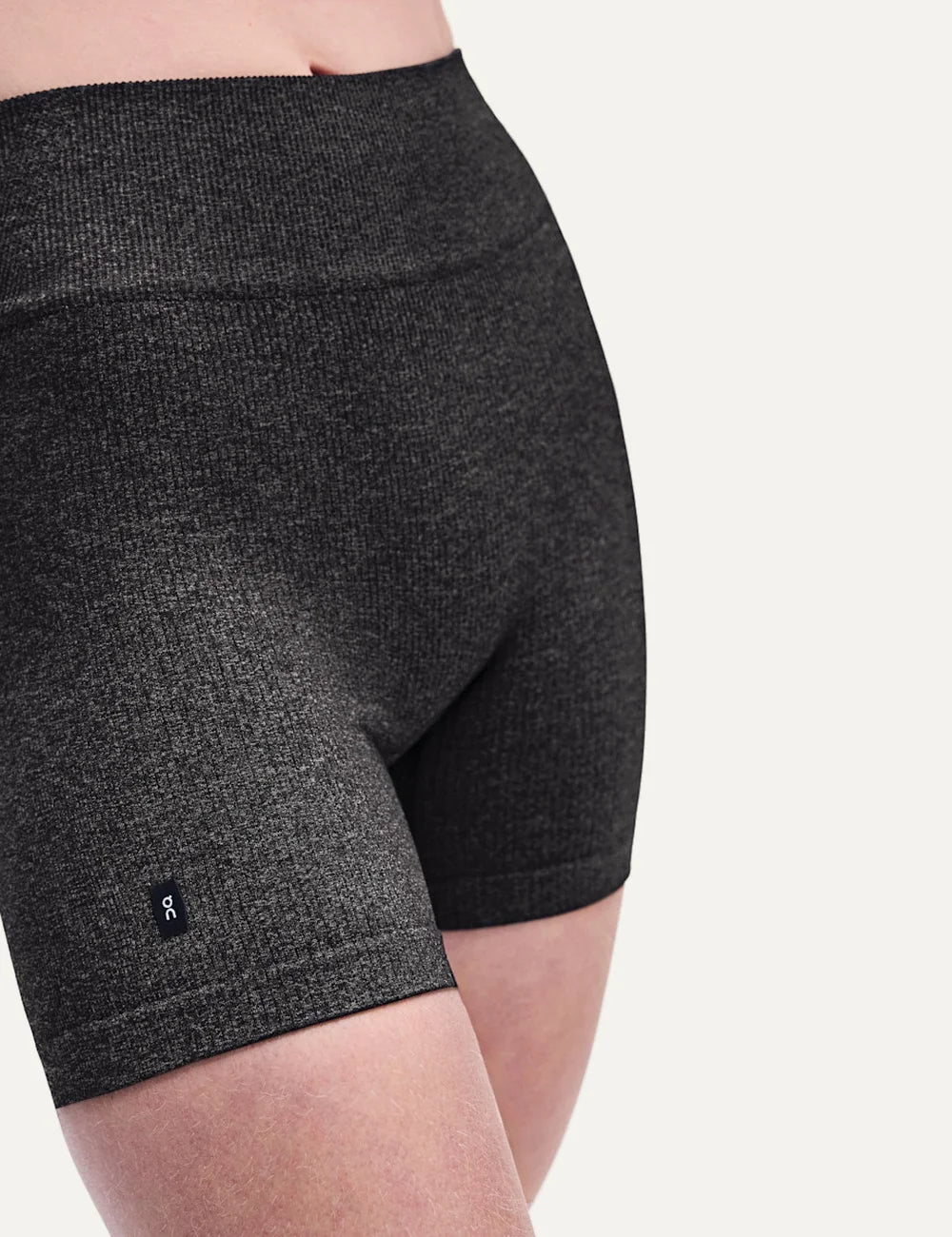 On women's dark grey heathered high-waisted biker shorts with close fit, soft textured knit, seamless feel, four-way stretch fabric and On logo detail