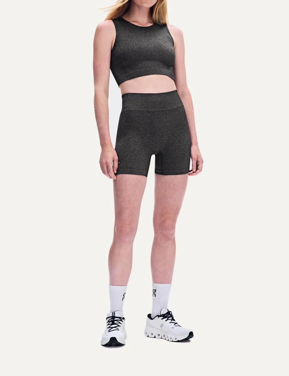 On women's dark grey heathered high-waisted biker shorts with close fit, soft textured knit, seamless feel, four-way stretch fabric and On logo model