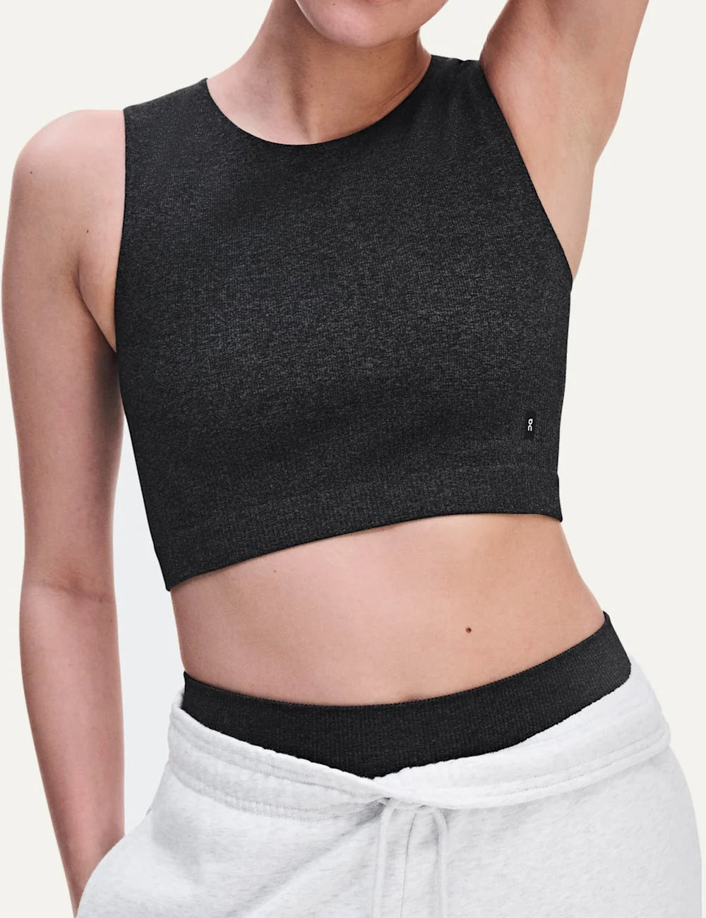 On women's dark grey heathered crop athletic top with sleeveless design, round neckline, soft textured knit, four-way stretch fabric and bonded edges detail
