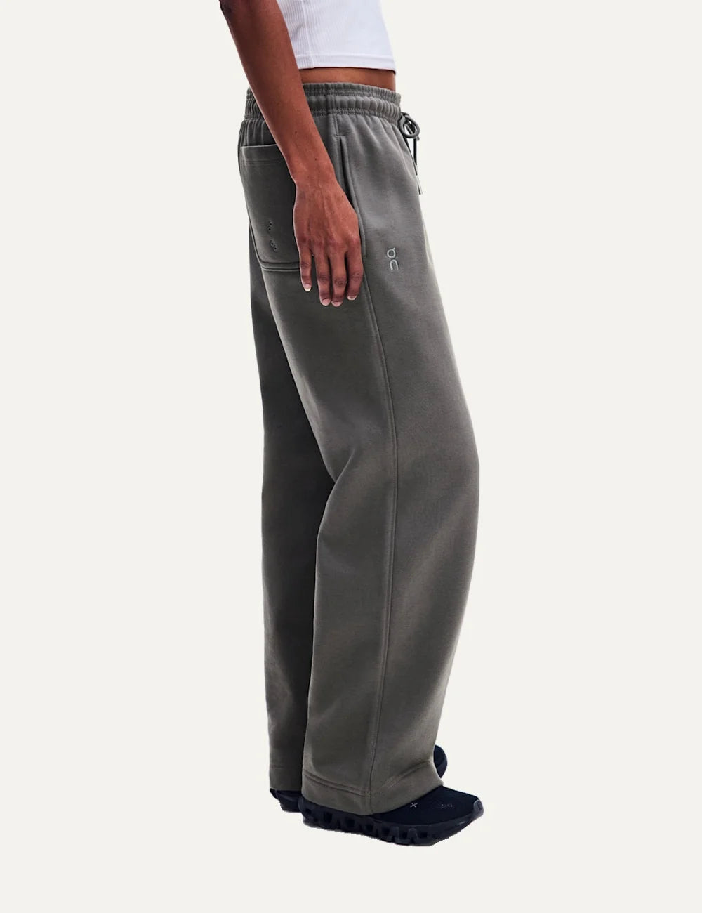 On women's grey relaxed fit sweatpants with wide straight legs, elastic drawstring waistband, soft brushed lining, side pockets and embroidered logos side