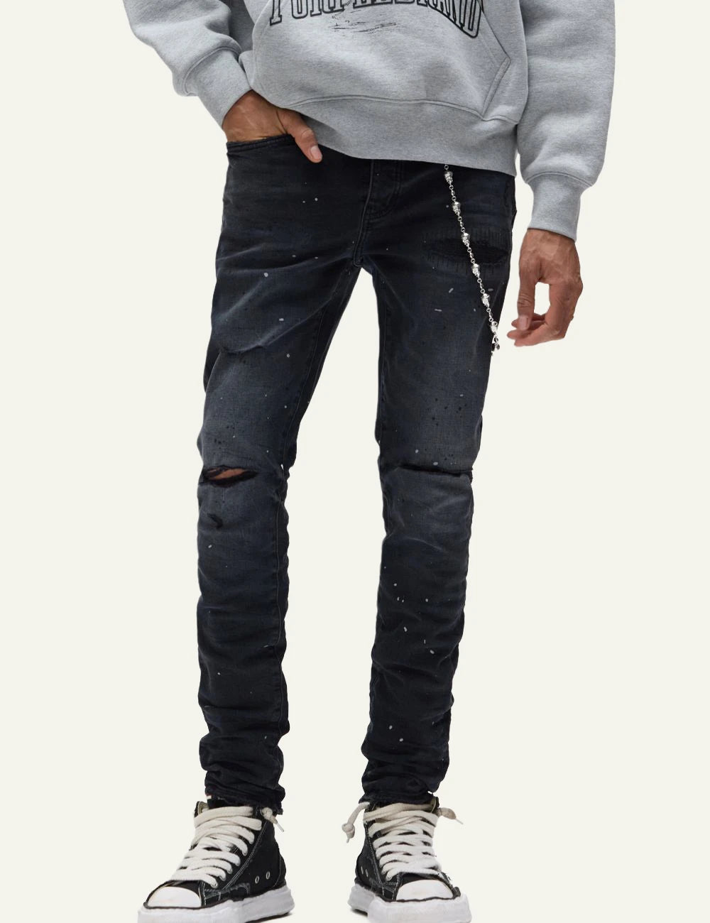 Purple Brand black skinny jeans with distressed knees and paint splatter front detail view