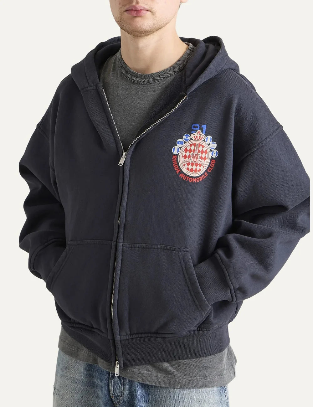 Rhude men's dark grey cotton zip-up hoodie with Automobile Club crest graphic, kangaroo pockets and ribbed trims model