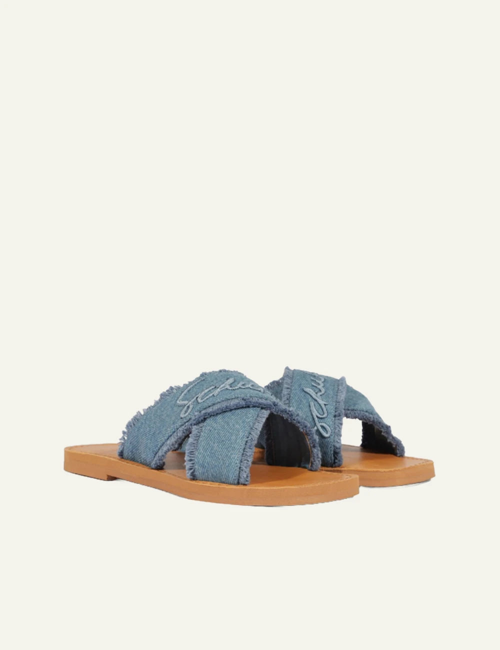 Schutz denim flat sandal with frayed X straps and logo detail angled view