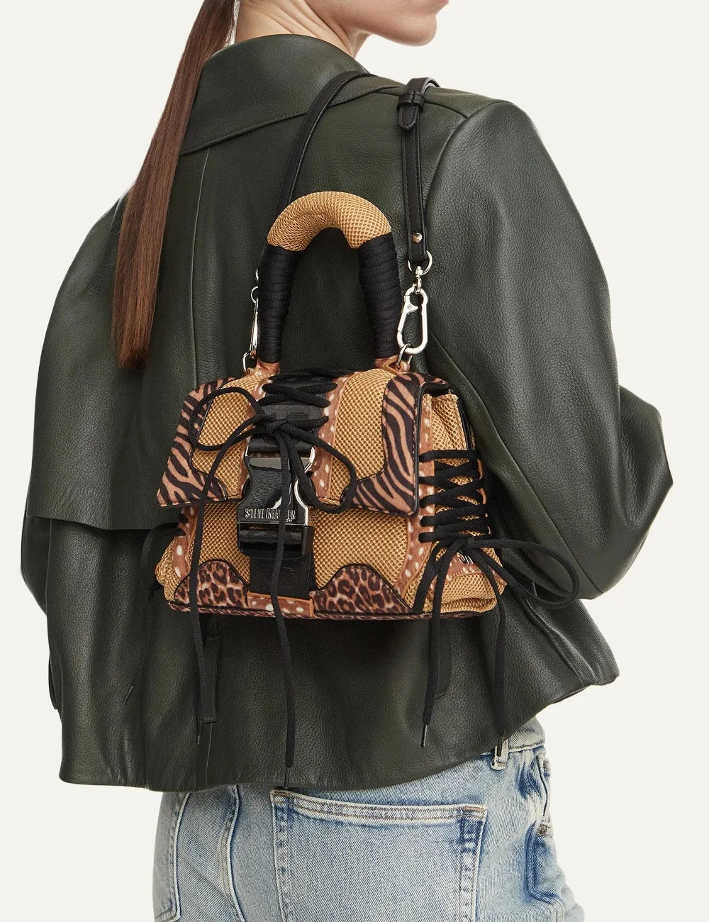 Steve Madden Bdiego M women's brown animal print handbag featuring leopard and zebra patterns, beige mesh panels, black lace-up details, padded top handle, metal buckle closure and adjustable shoulder strap, on model