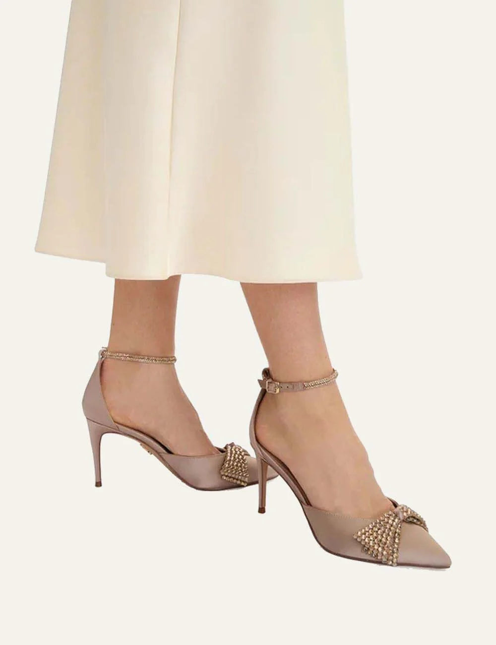 Steve Madden Last Dance women's beige satin-look pointed-toe pumps featuring sparkling rhinestone embellishment, adjustable ankle strap with gold-tone buckle and high stiletto heel, on model