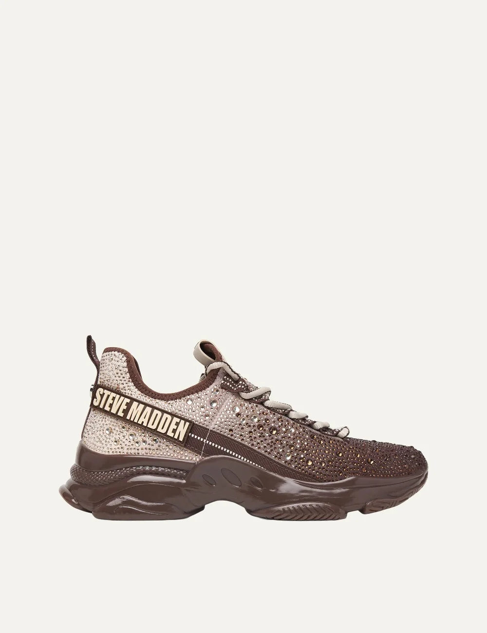 Steve Madden Mistica women's chunky sneakers in brown and taupe, embellished with sparkling rhinestones, featuring a gradient textile upper, beige and brown laces, oversized Steve Madden side logo and glossy brown sculpted sole, side view.