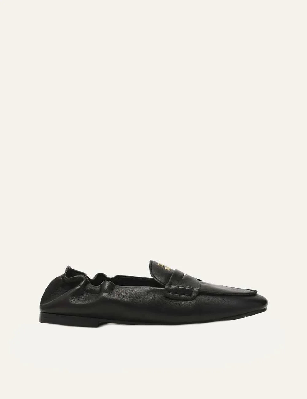 Steve Madden women's black leather loafers with gold-tone metal detail on penny strap, gathered heel, rounded toe and flat black rubber sole, side view.