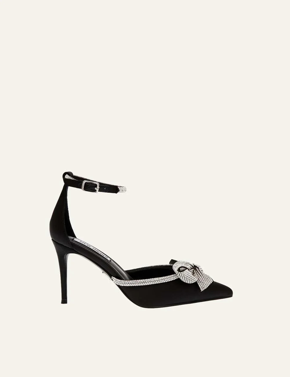 Steve Madden women's black satin pointed toe pumps with sparkling rhinestone bow, crystal embellished trim, adjustable ankle buckle strap and 9 cm stiletto heel, side view.