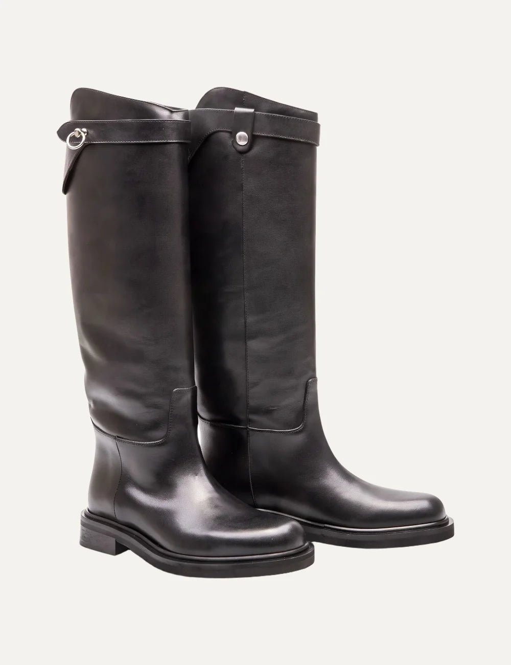 Women's black smooth leather knee-high boots with round toe, low block heel, asymmetric shaft and silver-tone ring strap detail angled
