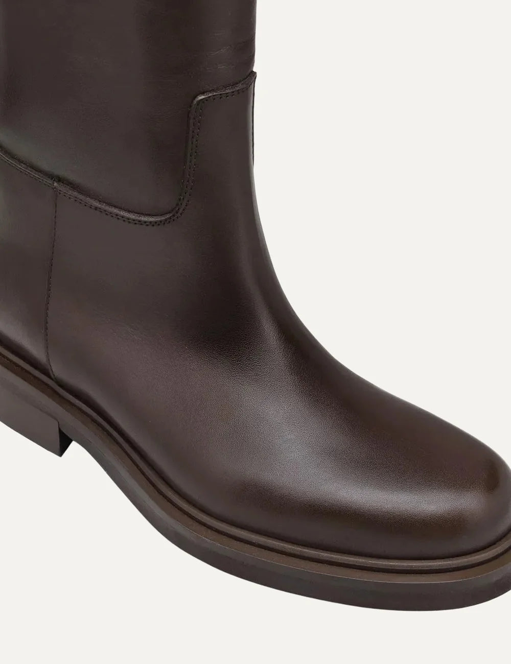Women's dark brown smooth leather knee-high boots with round toe, low flat heel, asymmetric shaft and silver-tone ring strap detail angled