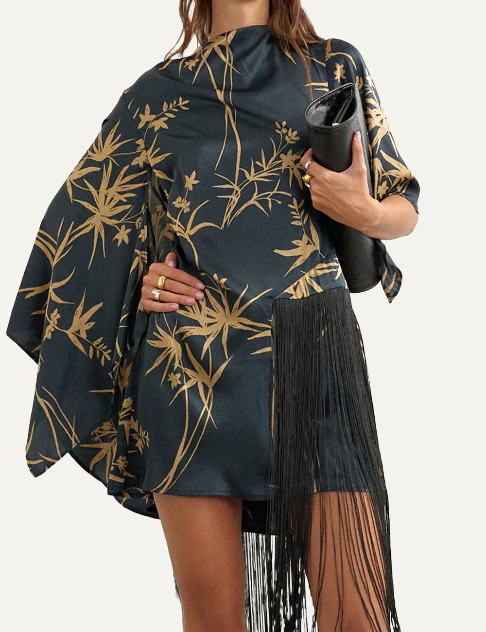 Women's dark grey satin mini dress with beige botanical print, asymmetric cape sleeve and long black fringe detailing.
